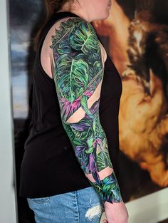 a woman with a tattoo on her arm and shoulder is standing in front of a painting