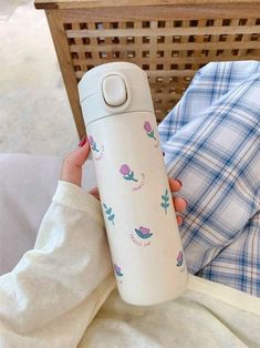 a person holding a water bottle in front of a basket with clothes on the floor