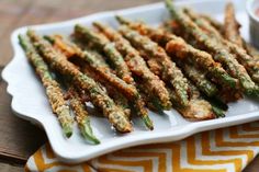 fried asparagus on a white platter with dipping sauce