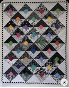 a black and white quilt with many different colors on it's sides, including one in the center