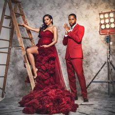 a man in a red suit standing next to a woman in a red dress on a ladder