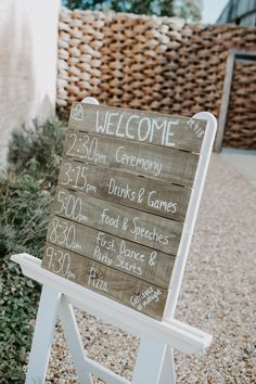 a wooden sign sitting on top of a gravel road next to a building and bushes