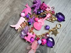 "This beautiful charm bracelet was lovingly made by me. It's got a stainless steel gold colored chain bracelet with varying shades of pink and purple charms. I call these \"toy box\" charm bracelets because many of the charms look like they're right out of a toy box. Lots of fun things to fidget with. This bracelet is made from a mix of vintage and new charms, found objects. ------------------------------- Ghost Candy Creations, be unapologetically you! If you have any problems with your item on Trendy Pink Jewelry With Charms, Trendy Pink Charm Necklace With Lobster Clasp, Trendy Pink Charm Bracelets, Trendy Pink Bracelets With Charms, Playful Pink Charm Bracelet For Gift, Pink Dangling Charms For Gifts, Pink Dangle Charms For Gifts, Handmade Pink Adjustable Charms, Playful Pink Charm Bracelet As Gift