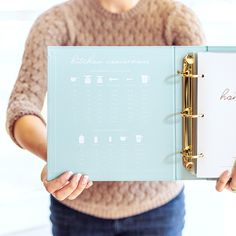 a woman is holding a planner in her hands