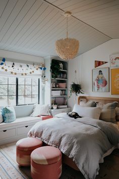 a bedroom with a bed, window and ottoman