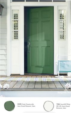 a green front door on a white house with wood flooring and two lights above it