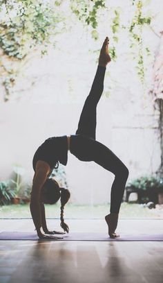 a woman doing a yoga pose with her hands in the air while standing on one leg