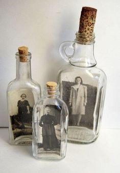 two glass bottles with pictures in them sitting next to each other