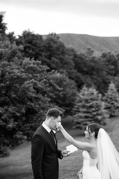 a bride and groom feeding each other cake at their outdoor wedding in the mountains, black and white photo