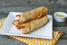 two burritos on a plate with dipping sauce