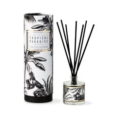 an image of a candle and reeds in front of a box with the label tropical paradise