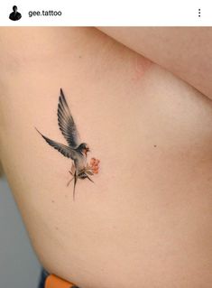 a small bird tattoo on the side of a woman's stomach, with an orange flower in it