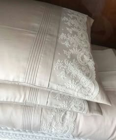 two pillows with white lace on them sitting next to each other