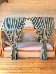 a wooden bunk bed with blue drapes and pom poms