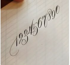 someone is writing on a piece of paper with the numbers in cursive handwriting