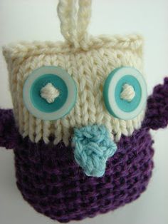 a crocheted owl hat with buttons on it's ears and eyes is hanging from a hook