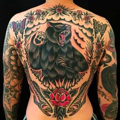 the back of a man's body with tattoos on it and an image of a bear