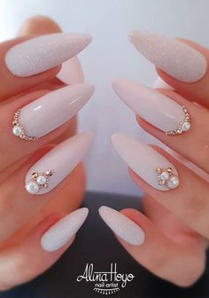 a woman's hands with long, white nails and some gold decorations on them