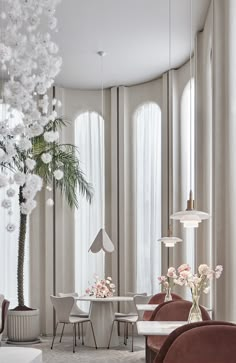 an elegant dining room with white flowers in vases on the table and chairs around it