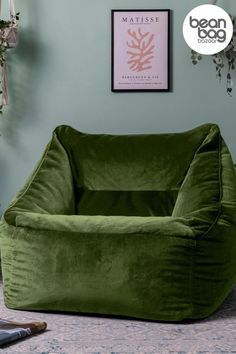 a large green bean bag chair sitting on top of a carpeted floor next to a plant