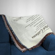 a blue couch with a harry potter blanket on it's back and the hogwarts script written in cursive writing