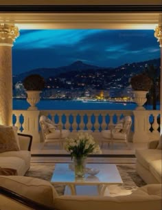 a living room filled with furniture and a view of the water at night in the distance