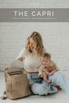 a woman holding a baby in her lap while sitting on the floor with a purse