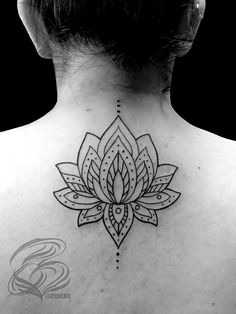 the back of a woman's neck with a lotus tattoo on it