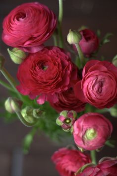 a bunch of red flowers are in a vase on a table, with the stems still attached