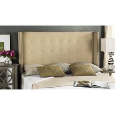 the headboard is upholstered with gold trimmings and has two pillows on it