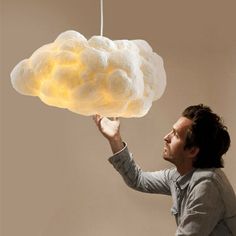 a man holding up a cloud shaped light above his head