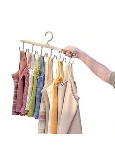 a person holding an umbrella and hanging clothes on a rack