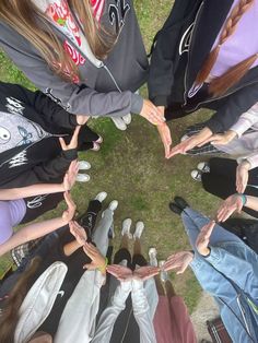 a group of people standing in a circle holding their hands up to form a heart