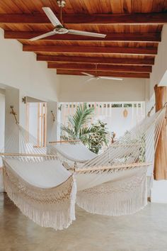 two white hammocks in a room with wood ceilinging and wooden beams on the ceiling