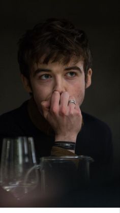 a man sitting at a table with a wine glass in front of him and his hand on his face