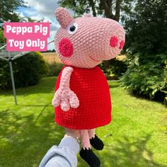 a crocheted peppa pig toy is being held by someone's hand