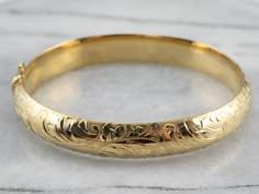 "Stunning! The details on this vintage 18 karat gold bangle are simply gorgeous! Intricate botanical designs are engraved in warm yellow gold, covering the entire bracelet. Beautiful on its own or layered with other bracelets this piece is perfect for day or evening wear. Metal: 18K Yellow Gold Width: 11.1 mm Inside Circumference: 7 Inches Marks: \"GERMANY 18KO \" Stamped To view a video of this piece check out the link below: https://vimeo.com/530900365 SKU #: JL4WMETT Each piece has been ident Luxury Engraved Brass Bracelets, Luxury Brass Bangle Gift, Luxury Brass Engraved Bracelets, Luxury Engraved Spiritual Bangle, Luxury Spiritual Engraved Bangle, Affordable Brown Engraved Jewelry, Luxury Gold Bracelets With Engraving Option, Luxury Gold Bracelet As Gift With Decorative Band, Luxury Gold Sentimental Bracelets