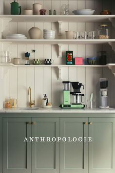 a kitchen with green cabinets and shelves filled with cups, saucers, and other items