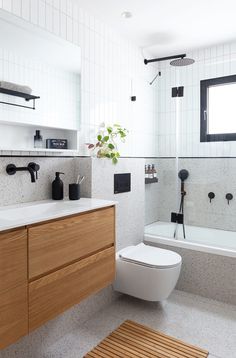 a bathroom with a toilet, sink and bathtub next to a wooden mat on the floor