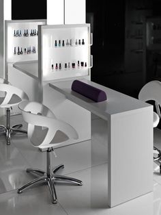 a salon with white chairs and bottles of nail polish on the wall behind the counter