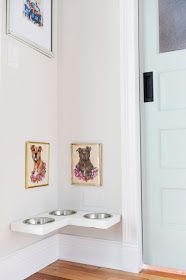 two dogs are sitting in their bowls on the wall next to each other with pictures above them