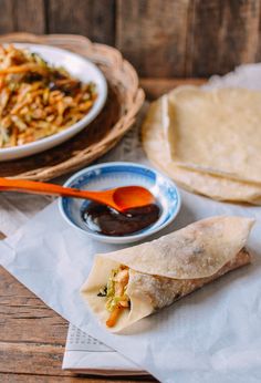 two burritos and some dipping sauce on a table