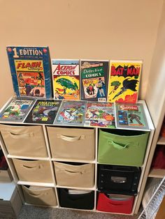 a collection of comic books sitting on top of a white dresser next to a wall