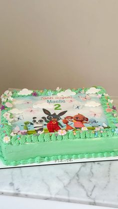 there is a green cake with cartoon characters on the frosting and icing, sitting on top of a marble table