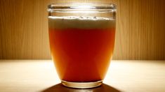 a glass filled with liquid sitting on top of a wooden table