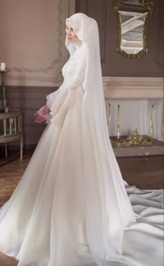 a woman in a white wedding dress and veil standing on a floor with a mirror behind her