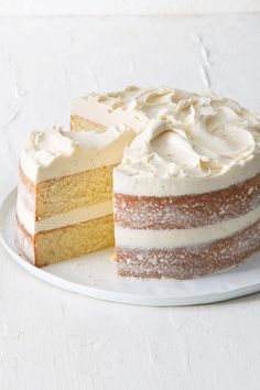 a cake with white frosting sitting on a plate next to a slice cut out of it