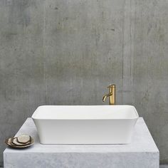 a white sink sitting on top of a cement counter next to a faucet