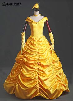 a yellow dress is on display in front of a gray background with an orange flower