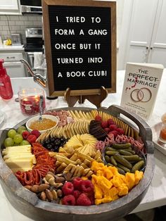 a platter filled with lots of different types of food next to a sign that says i tried to form a gang once but it turned into a book club